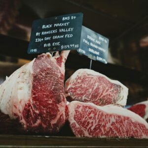 Close-up of premium rib eye steaks displayed at a retail market with signage.