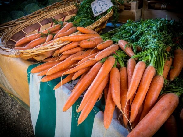 Vibrant fresh carrots on sale at a local farmers market, showcasing organic produce.